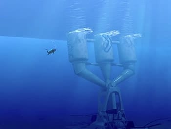 Underwater view of a large, industrial ocean turbine structure anchored to the seafloor, designed to harness energy from ocean currents.