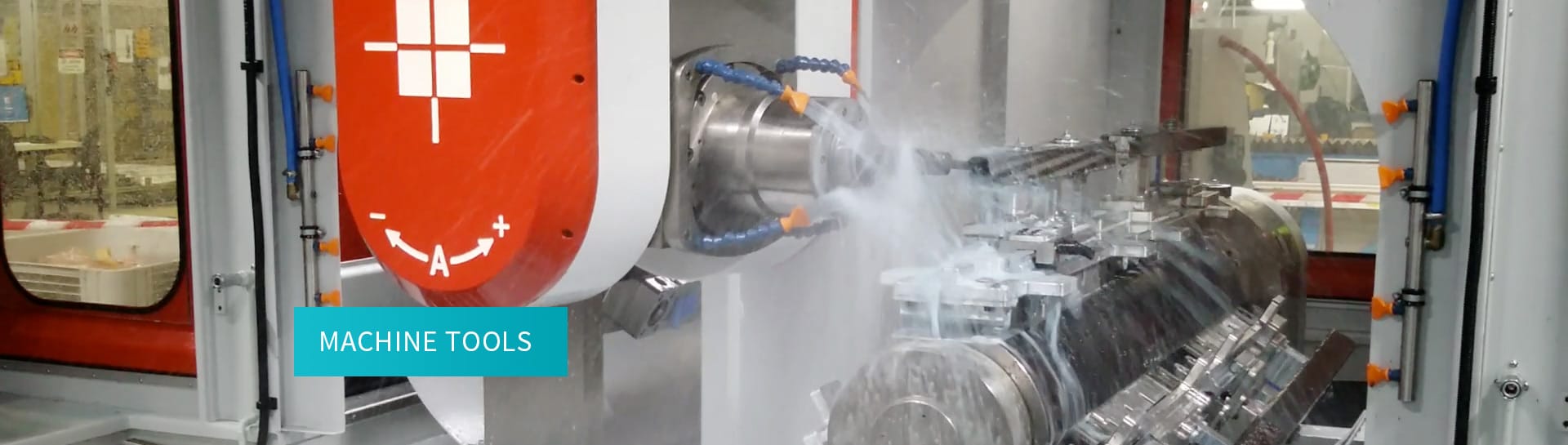 Close-up of a machine tool operating on a cylindrical metal component with coolant spray actively applied.